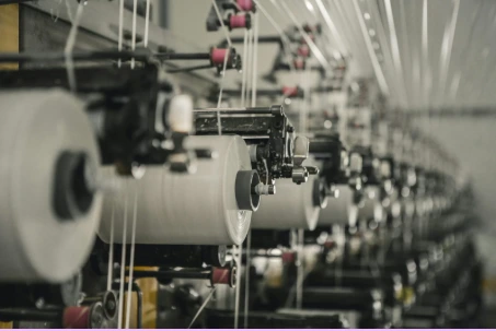 Industrial sewing machinery line with operators stitching bulk garments in a textile manufacturing factory