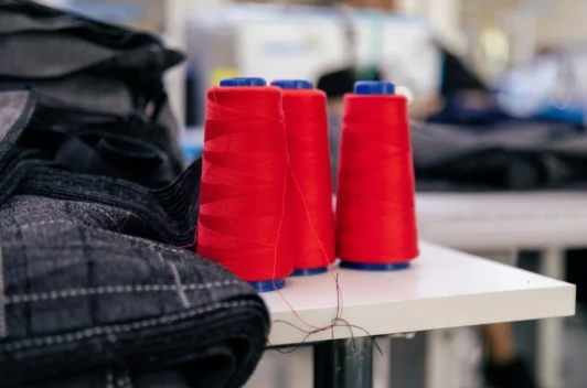 Red thread spools on industrial sewing machines in a textile manufacturing factory